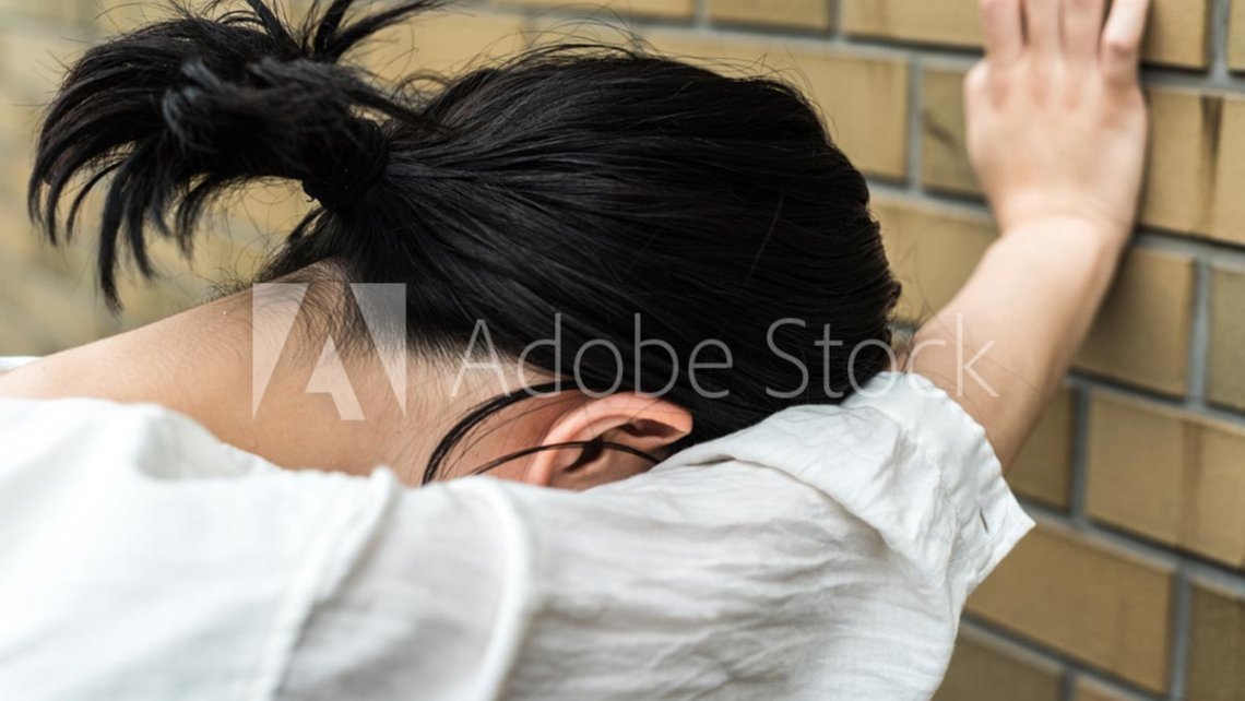 Dizzy woman resting against wall